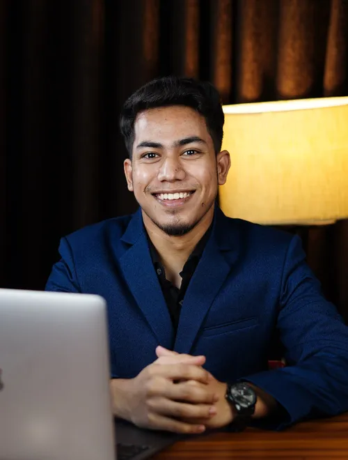 Miraj smiling at his desk with a laptop
